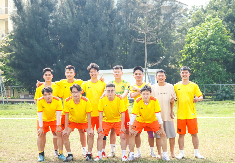 A group of men in yellow shirts and orange shorts posing for a photo

Description automatically generated